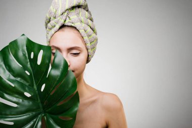 Kafasındaki bir havlu ile genç kız tutan bir büyük yeşil yaprak, gün spa