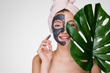 pembe havlu başında gülümseyen bir kızla bir kil nemlendirici maske uygulanan