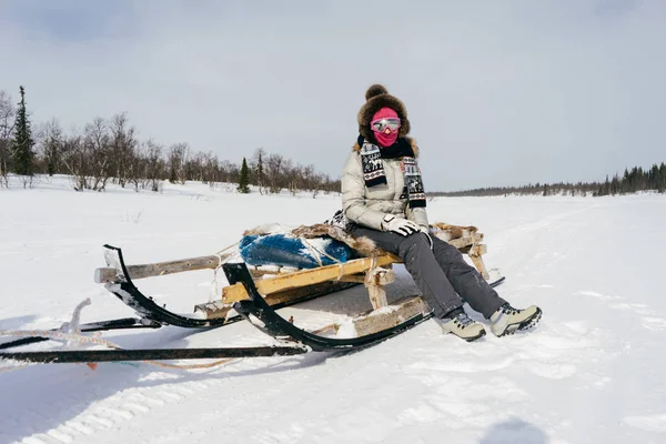 Een meisje in warme kleren noorden reist, zit op een slee, — Stockfoto