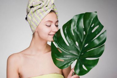 holding bir büyük yeşil yaprak, gün spa başında bir havlu ile sevimli gülümseyen kız