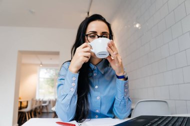 genç kız öğrenci okuldan sonra bir kafede mavi bir gömlek ve gözlük içecekler kahve