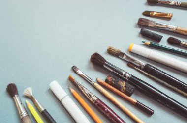 Mavi yüzeyde birçok Sanat fırçalar, kalemler ve işaretleyiciler vardır
