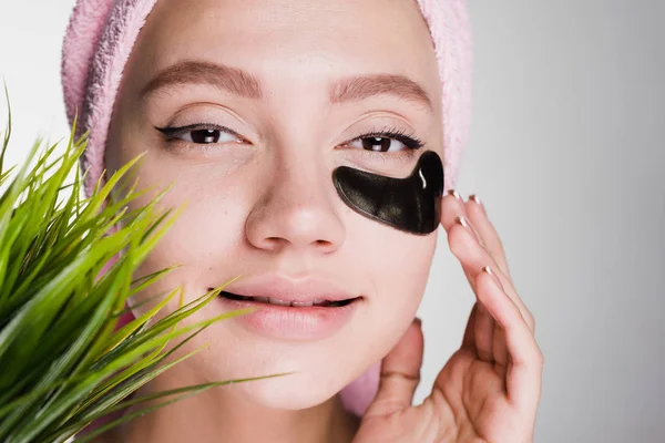 Jovem atraente com uma toalha rosa na cabeça sorrindo sob os olhos de manchas pretas — Fotografia de Stock