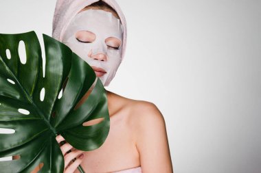 genç kızın yüzünde bir doku maske kafasındaki bir havlu ile yaprak yeşil tutar
