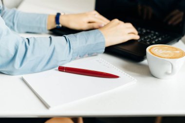 Kız serbest meslek mavi gömlekli laptop, yakın Kupası kahve ile çalışma