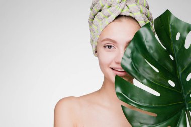 holding bir yaprak yeşil, gün spa başında bir havlu ile güzel gülümseyen kız