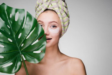 onun gözleri beyaz yamalar yaprak yeşil, gün spa.under tutan başında bir havlu ile güzel gülümseyen kız