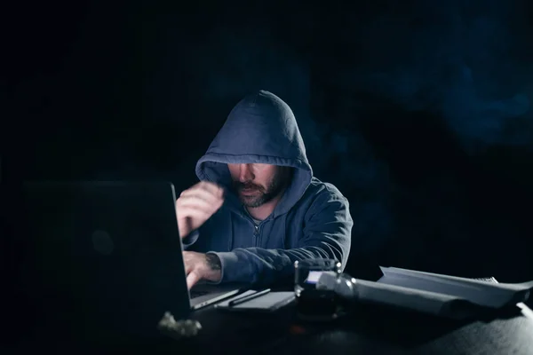 Um criminoso misterioso faz algo ilegal num portátil, um hacker, no escuro — Fotografia de Stock