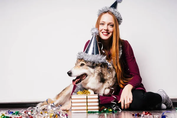 Happy red-haired woman sits on the floor with her dog, New Year 's atmosphere — стоковое фото