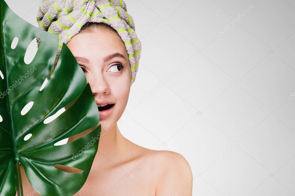 cute young girl with a towel on her head holds a green leaf in her hand, a day spa