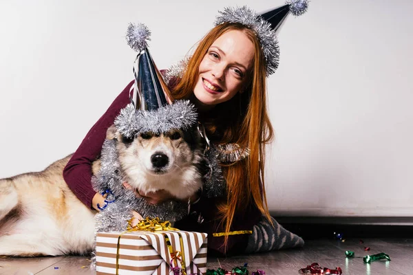 Счастливая рыжая девушка обнимает свою собаку, празднуя новый 2018 год — стоковое фото