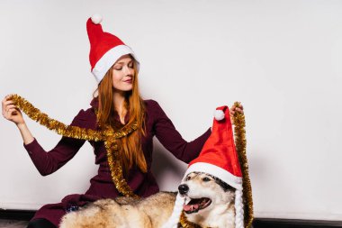 köpeğini, yeni yıl atmosfer, Noel Baba gibi kırmızı kapaklar ile oynarken güzel kızıl saçlı kız