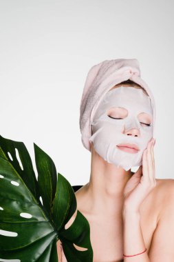 Kafasındaki bir havlu ile çekici güzel kız yüzünü sonra yüzünde doku maske görünüyor
