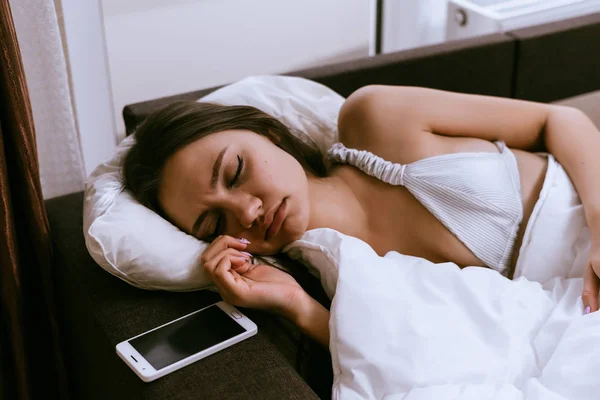 Menina sonolenta triste encontra-se na cama, não quer se levantar de manhã cedo — Fotografia de Stock