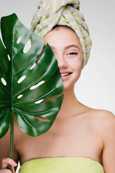 Szczęśliwy Ładna dziewczyna z ręcznikiem na głowie, przytrzymując zielony liść, day spa, Pielęgnacja twarzy — Zdjęcie stockowe