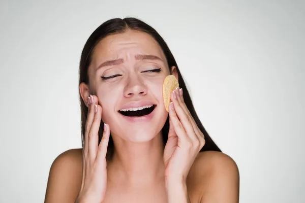 sweet laughing girl clears the skin on the face with the help of a sponge