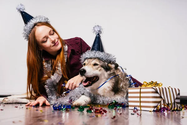 Fille aux cheveux roux assise sur le sol avec son gros chien, atmosphère du Nouvel An — Photo