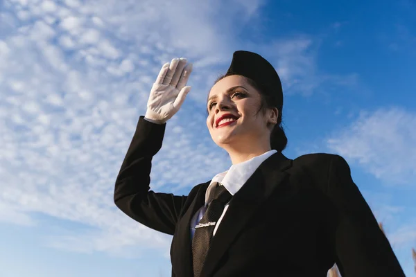 Happy young woman stewardess in uniform waiting for her flight, under the sky — Stock Photo, Image