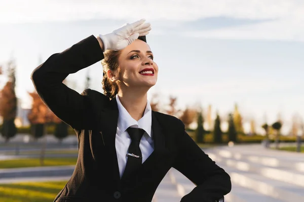 Happy krásná letuška dívka v uniformě, čeká na její let při pohledu na oblohu — Stock fotografie