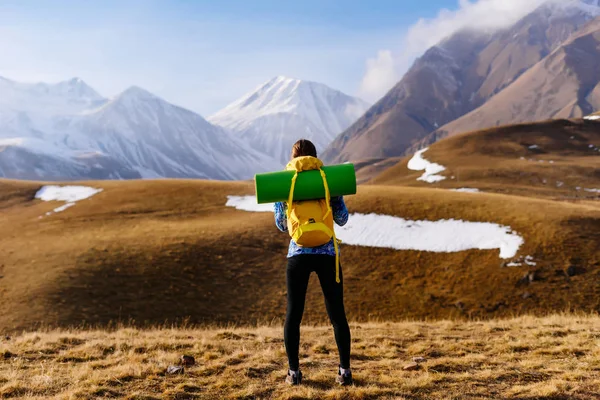 Joven activa en una chaqueta azul viaja a lo largo de la cresta del Cáucaso con una mochila y tienda de campaña —  Fotos de Stock