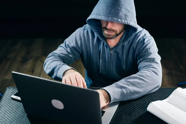 Gizemli sakallı adam yüzünü başlık altında gizler, laptop kesmek — Stok fotoğraf