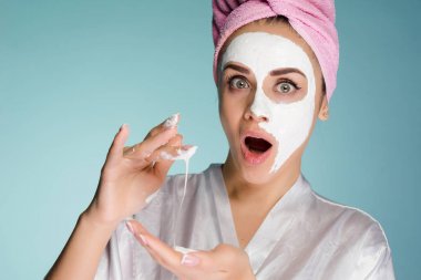Beyaz bir maske yüzünde nemlendirici uygulayarak başında pembe havlu ile sürpriz genç kız