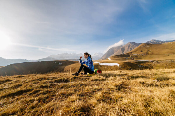 active young girl in a blue jacket enjoying nature and the Caucasus Mountains