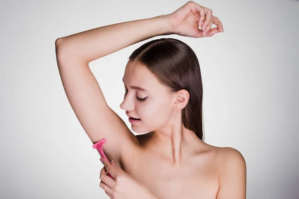 Fiatal lány leborotválja a haját a hónalj, egy borotvával — Stock Fotó