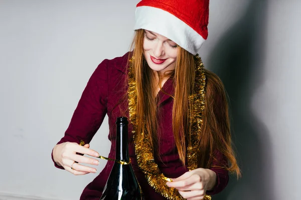 Щасливі дівчини з рудим волоссям у червоній кепці як Санта Клаус святкує новий рік з пляшку з шампанським — стокове фото