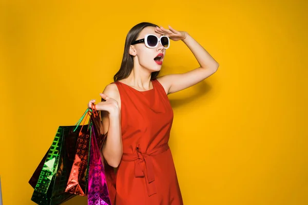 Een mooi meisje in een rode jurk en zonnebril zag grote kortingen — Stockfoto