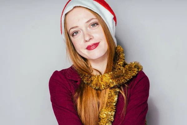 Linda menina ruiva com um boné vermelho como Papai Noel esperando por um ano novo e Natal — Fotografia de Stock