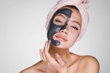 Kafasındaki bir pembe havlu ile çekici bir güzel kız bir kil maskesi uygulanmış