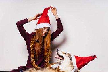 köpeğini, Noel Baba gibi kırmızı kapaklar ile yeni yıl atmosfer oturan mutlu Kızıl saçlı kız