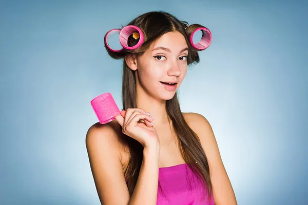 Привлекательная молодая девушка хочет красивую прическу, на голове розовые волосы бигуди — стоковое фото