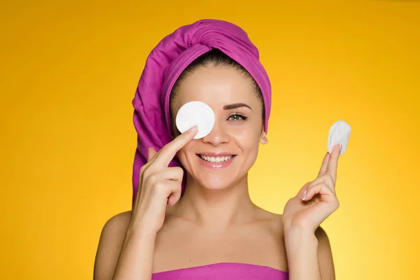 Happy smiling girl with pink canvas on her head holding white cotton-wool discs for cleansing the skin on her face — Stock Photo, Image