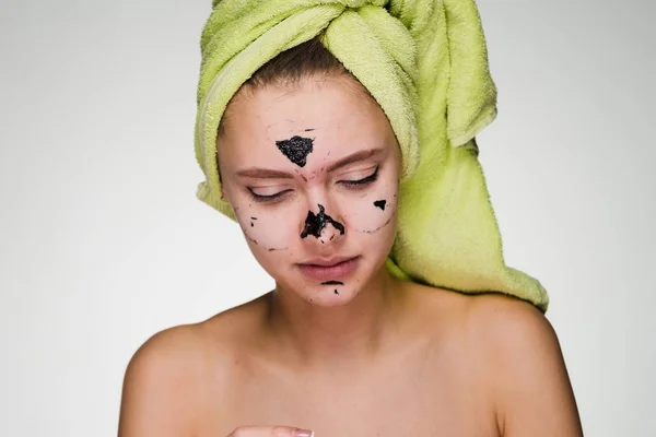 Una linda joven con una toalla verde en la cabeza se quitó la máscara negra contra el acné — Foto de Stock