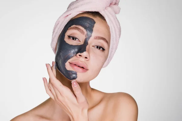 Uma jovem atraente com uma toalha rosa na cabeça aplicou uma máscara de barro útil — Fotografia de Stock