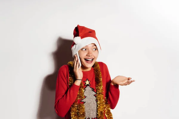 Divertida chica joven sorprendida en una gorra roja como Santa Claus hablando por teléfono, esperando el año nuevo — Foto de Stock