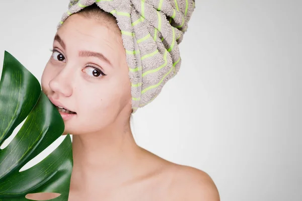 Słodkie piękna dziewczyna z ręcznikiem na głowie posiada zielony liść, day spa — Zdjęcie stockowe