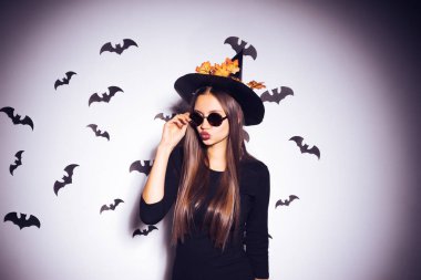 çekici sevimli kız cadı siyah şapka ve güneş gözlüğü Cadılar Bayramı için bekliyor