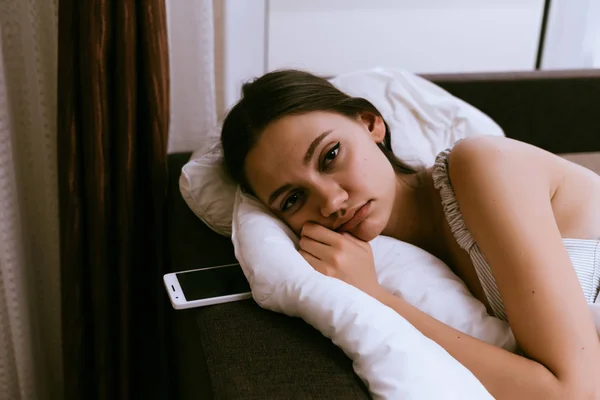 Schläfrig trauriges junges Mädchen wacht früh auf, liegt im Bett — Stockfoto