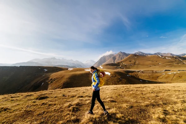 Счастливая девушка в синей куртке путешествует по Кавказским горам с рюкзаком и палаткой — стоковое фото