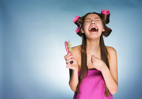 Молодая девушка плачет на голубом фоне из-за выпавших волос — стоковое фото