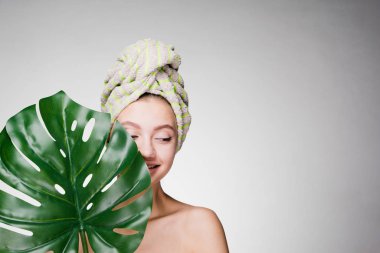 Kafasındaki bir havlu ile genç kız büyük bir yaprak tutar