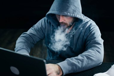 gizemli karanlıkta, bir nargile sigara adam hacker dizüstü kesmek sakallı