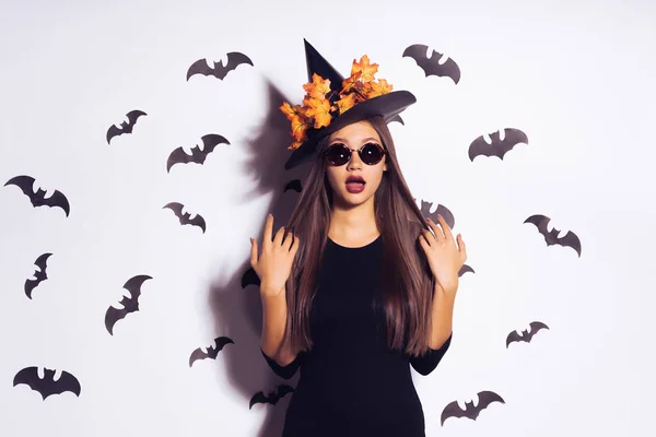 Surprise jeune fille sous la forme d'une sorcière pour Halloween, vêtements noirs et un grand chapeau — Photo