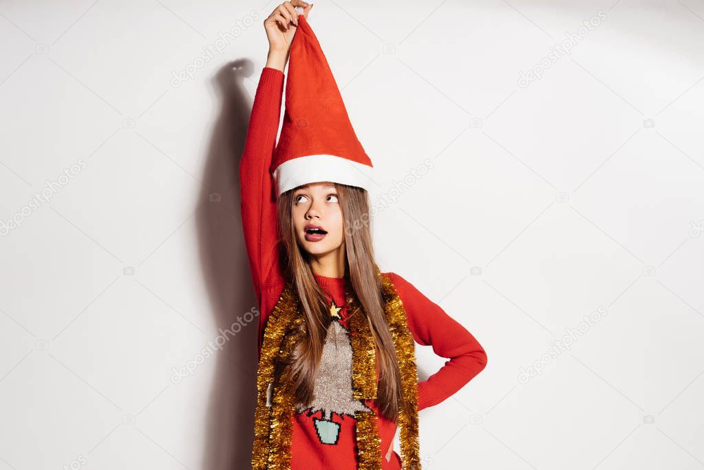 surprised young girl holding a red cap like Santa Claus, celebrating New Year and Christmas