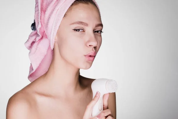 Funny rolig tjej med en rosa handduk på huvudet håller en elektrisk borste — Stockfoto