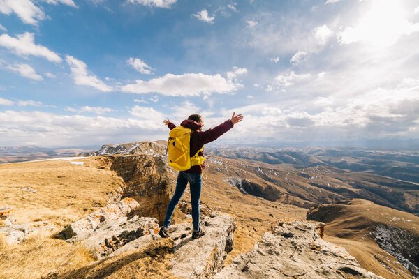 active young girl enjoys nature, travels through the Caucasus mountains, hands are raised upwards
