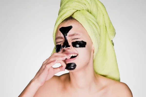 Sad young girl with a towel on her head removes a black mask from her face, it hurts — Stock Photo, Image